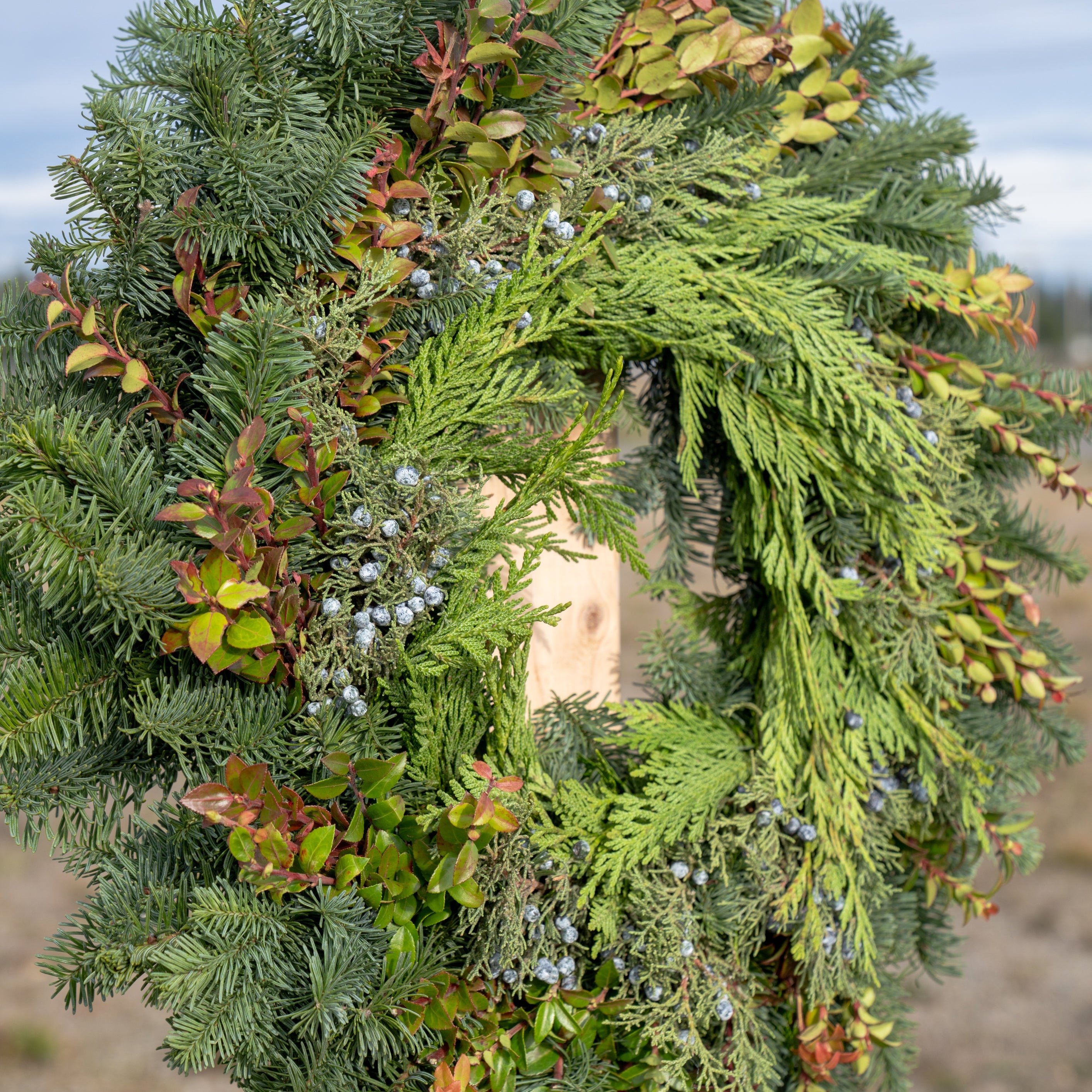 Green wreath with autumnal leaves against a blurred natural background