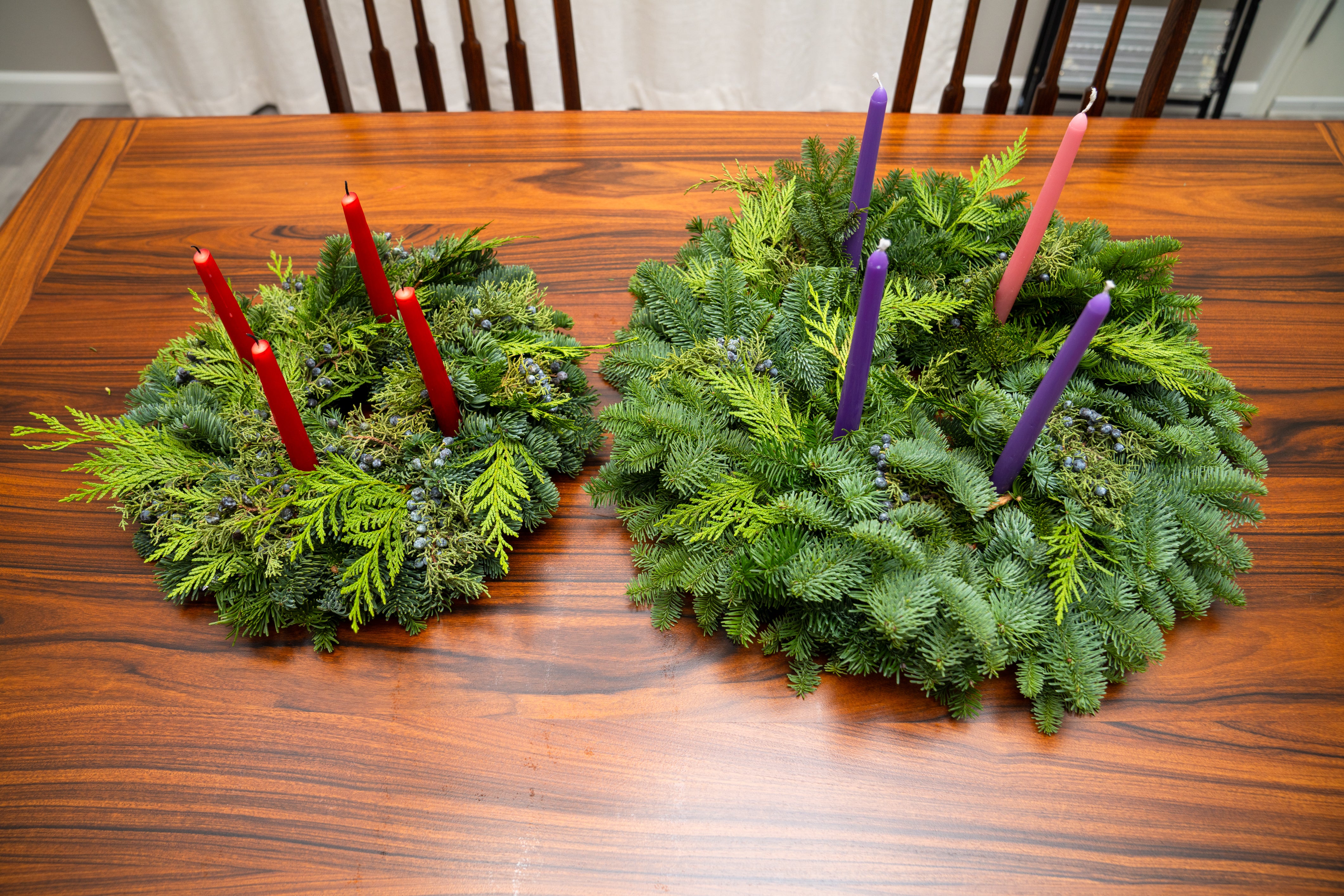 Two advent wreaths with candles on a wooden table