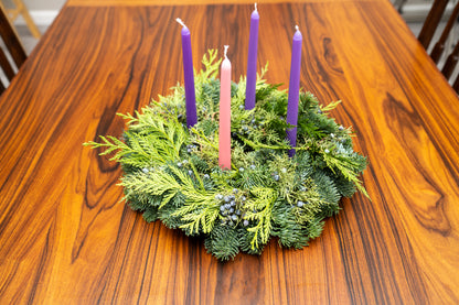 Advent wreath with four purple candles on a wooden table
