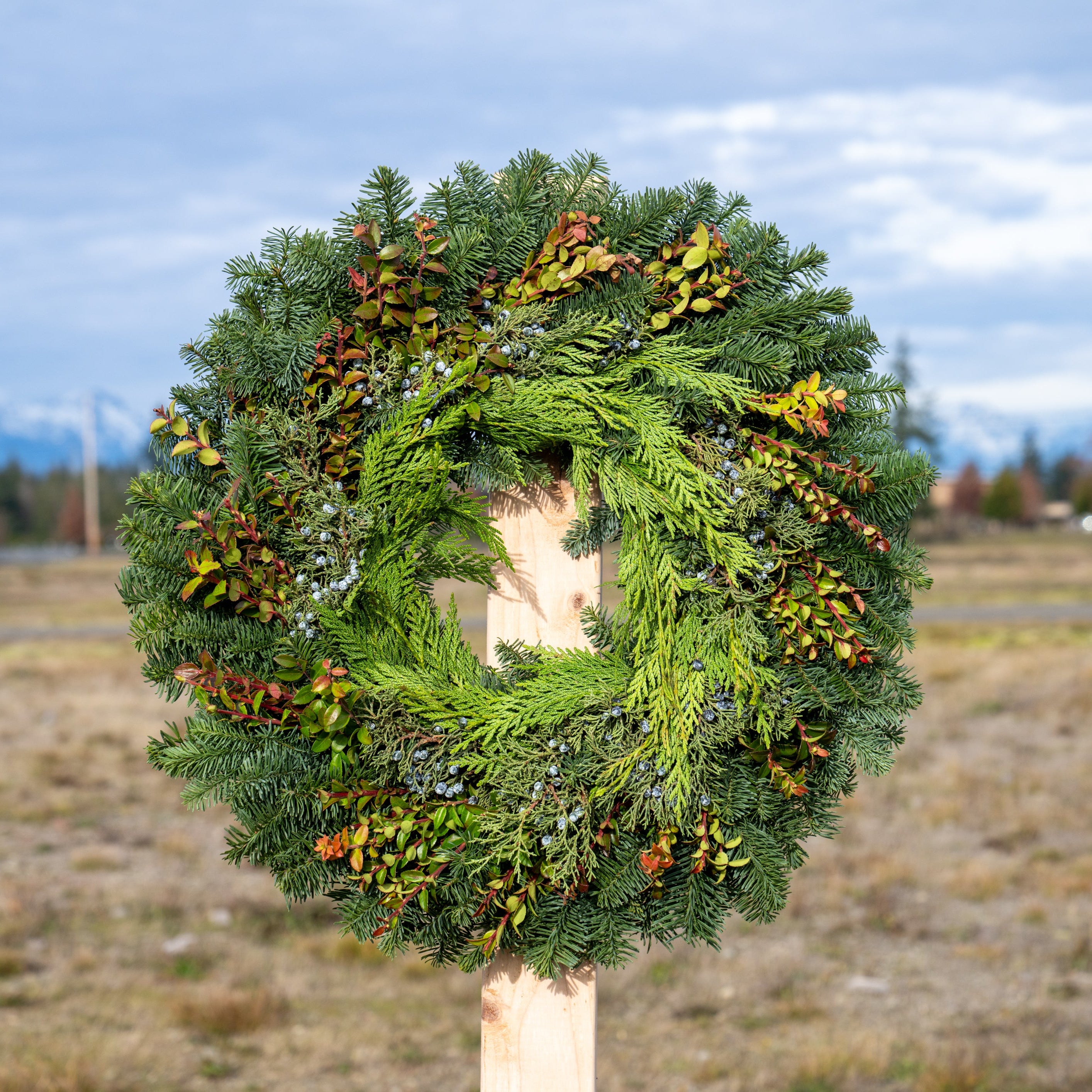Green wreath on a wooden post with a blurred natural background